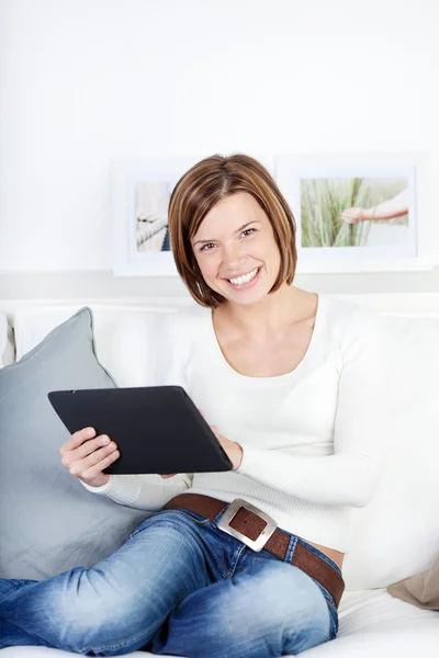 Jeune femme utilisant une tablette, assise sur le canapé — Photo