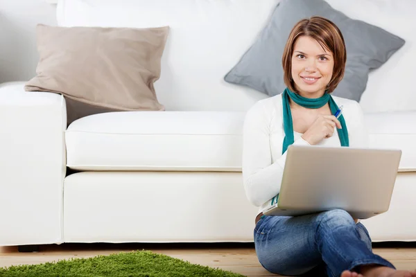 Lachende vrouw die werkt op de laptop in de woonkamer — Stockfoto