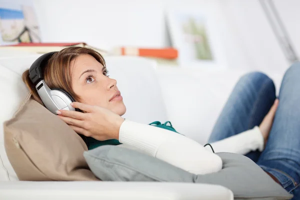 Mulher ouvindo música no sofá — Fotografia de Stock