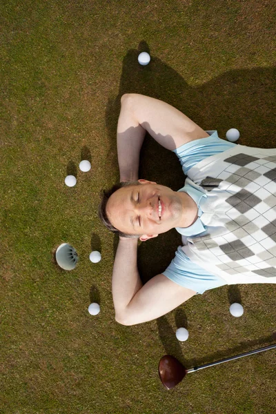 Mann mit Bällen und Schläger auf Rasen am Golfplatz liegend — Stockfoto