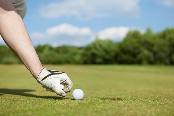 Mano del hombre poniendo pelota de golf en el agujero — Foto de Stock