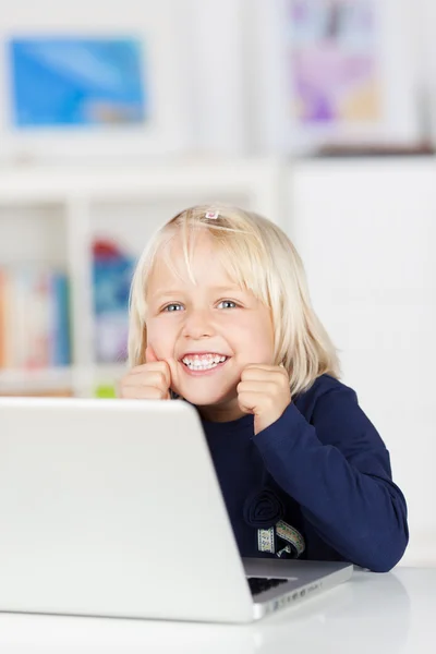 Glückliches junges Mädchen lächelt, während es einen Laptop benutzt — Stockfoto