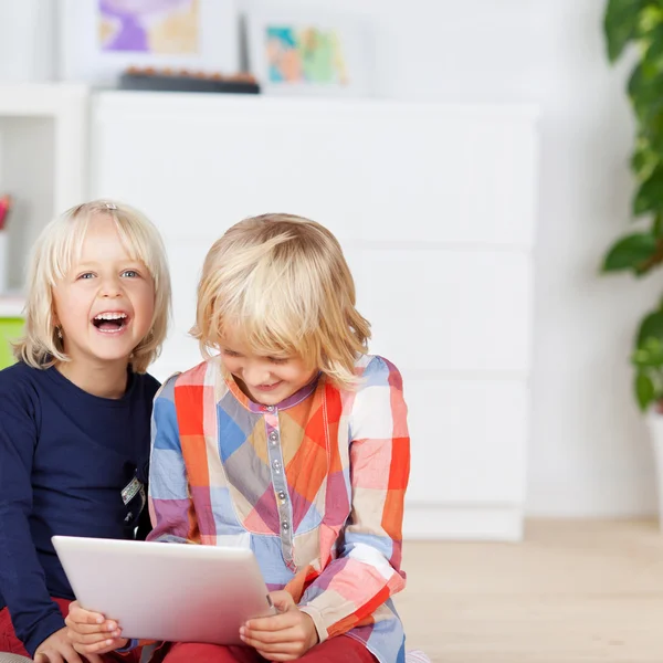 Ledsen tjej tittar på syskon med digital tablet — Stockfoto