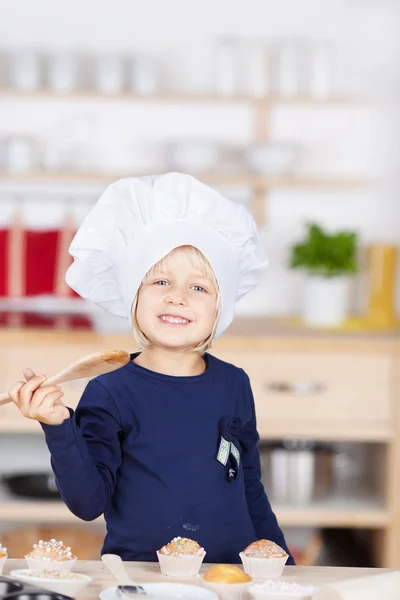 Mädchen mit Kochlöffel beim Cupcakes backen in der Küche — Stockfoto