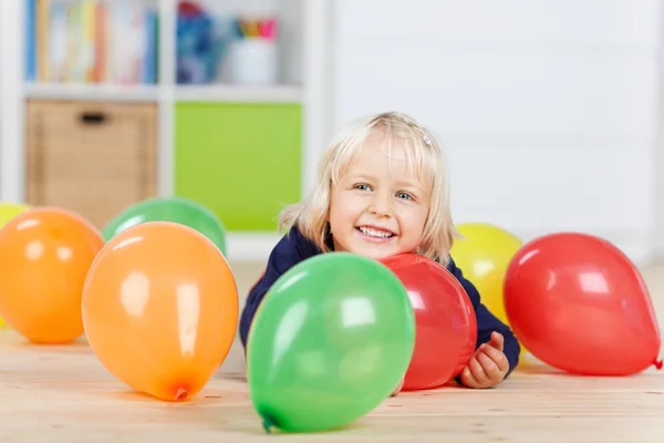 Meisje met kleurrijke ballonnen liggend op de vloer — Stockfoto