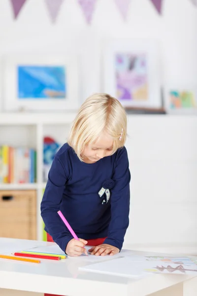 Дівчина малює на папері за столом — стокове фото