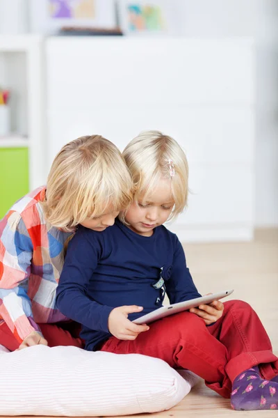 Menina usando tablet digital juntos enquanto sentado no travesseiro — Fotografia de Stock