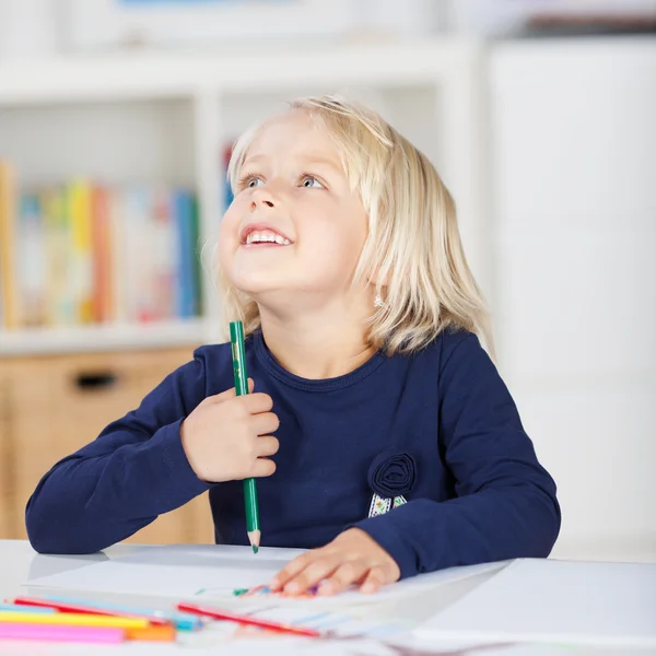 Menina segurando lápis de cor enquanto desenha na mesa — Fotografia de Stock