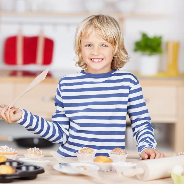 Menina segurando colher de madeira enquanto assa cupcakes — Fotografia de Stock