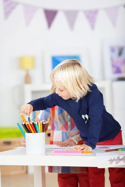Девушка выбирает цветной карандаш из органайзера на столе — стоковое фото