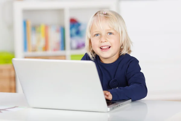 Meisje op zoek weg terwijl het gebruiken van laptop aan tafel — Stockfoto