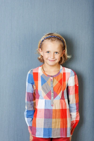 Girl Smiling While Standing Against Blue Wall Stock Image