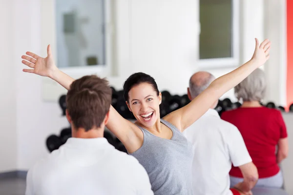 Mujer con brazos levantados sentada con grupo en gimnasio —  Fotos de Stock