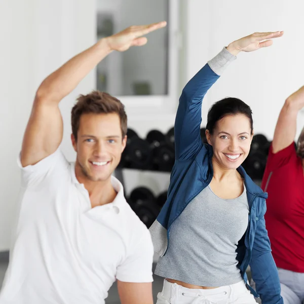 Grupo feliz haciendo ejercicio de estiramiento en el gimnasio — Foto de Stock