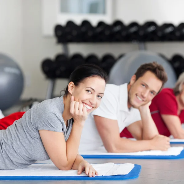 Vrouw met groep liggend op de mat te plaatsen bij gym — Stockfoto
