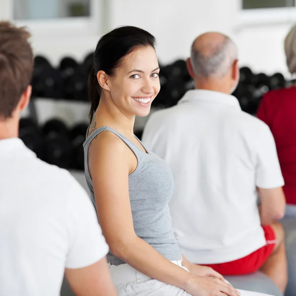 Femme souriant avec le groupe assis sur la balle de remise en forme — Photo