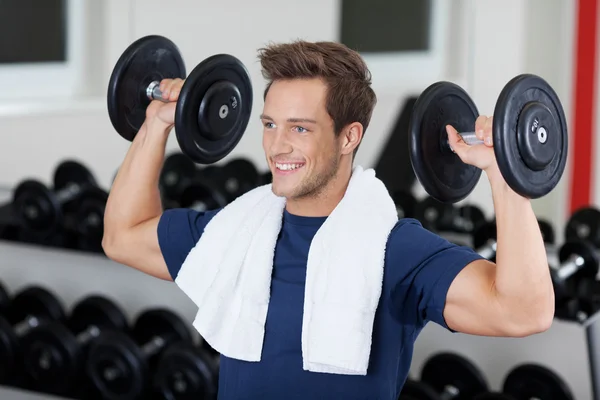 Homme levant haltères dans la salle de gym — Photo