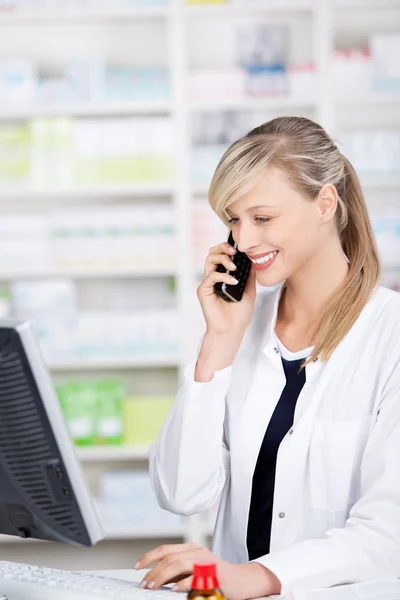 Smiling attractive pharmacist talking at the phone — Stock Photo, Image