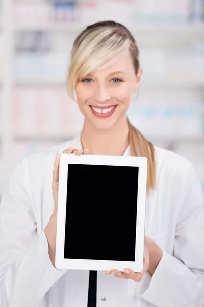 Farmacéutica sonriente sosteniendo una tableta en blanco —  Fotos de Stock