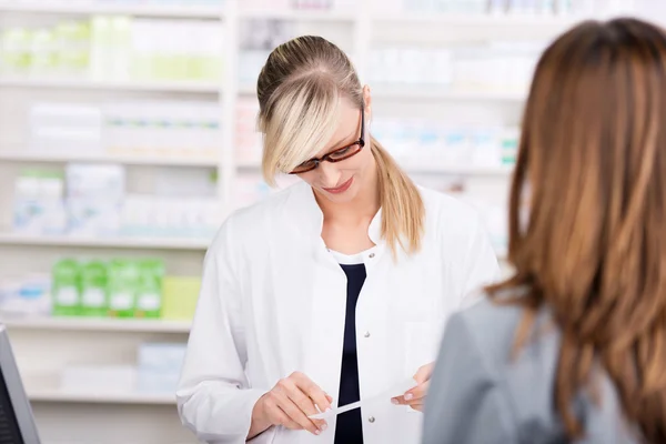 Kvinnliga apotekspersonal läser medicin recept — Stockfoto