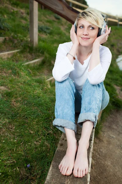 Usmívající se žena s sluchátka jezera — Stock fotografie