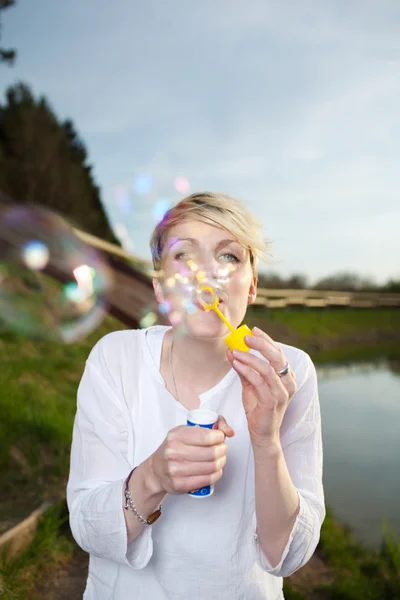 Счастливая молодая женщина делает мыльные пузыри — стоковое фото