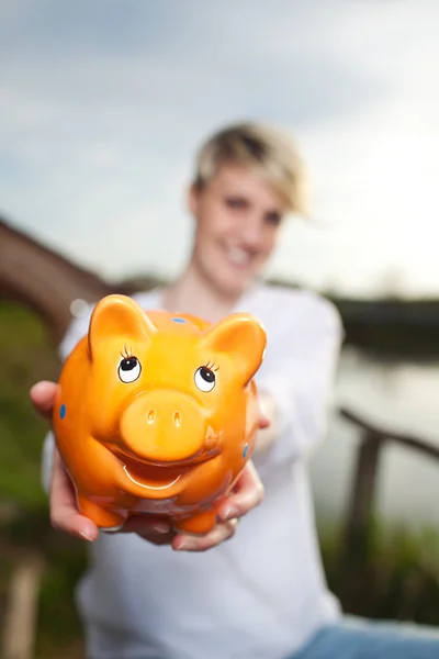 Jonge vrouw met piggy bank buiten — Stockfoto