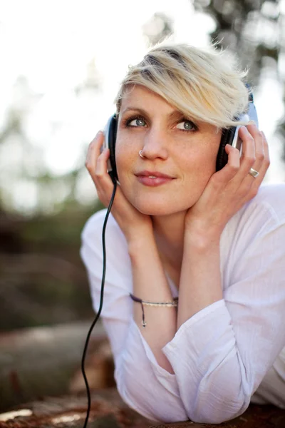 Mujer pensativa con auriculares acostado en el registro —  Fotos de Stock