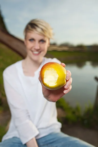 Mujer mostrando manzana por lago — Foto de Stock