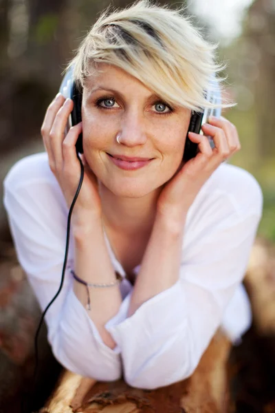 Zbliżenie kobiety ze słuchawkami leżącego na dziennika — Zdjęcie stockowe