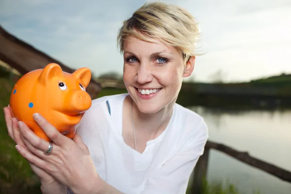 Jonge vrouw met piggy bank outdoors — Stockfoto