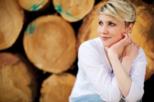 Doordachte vrouw tegen logboeken — Stockfoto