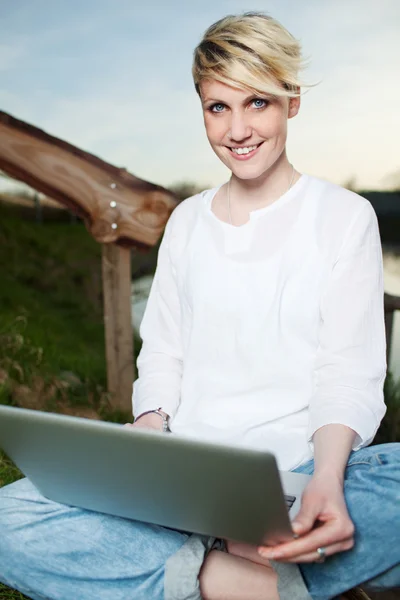 Χαμογελώντας γυναίκα χρησιμοποιώντας φορητό υπολογιστή σε εξωτερικούς χώρους — Φωτογραφία Αρχείου