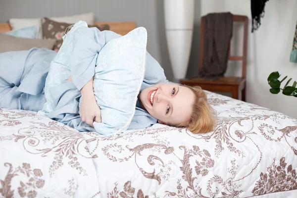 Mujer abrazando almohada mientras acostado en la cama — Foto de Stock