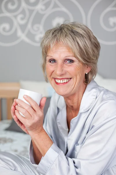 Äldre kvinna med kaffekopp i sovrum — Stockfoto