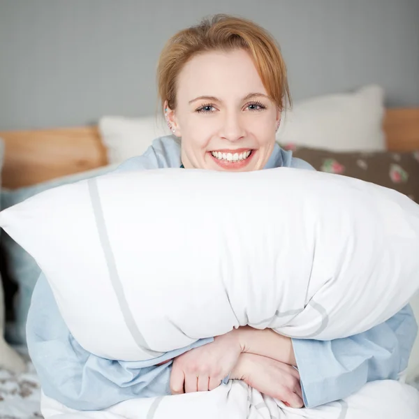 Mujer abrazando gran almohada mientras se acuesta en la cama — Foto de Stock