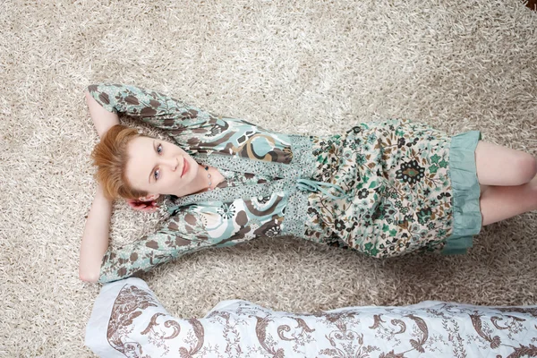 Atractiva joven mujer relajándose en la alfombra —  Fotos de Stock