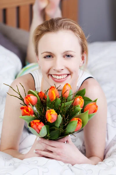 Frau hält Tulpenstrauß im Bett — Stockfoto