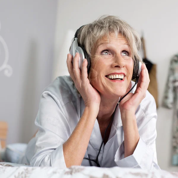 Donna in ascolto di musica attraverso auricolare a letto — Foto Stock