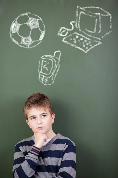 Student tegen schoolbord met bal, telefoon en computer getekende o — Stockfoto
