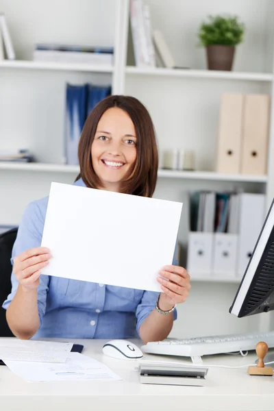 Empresaria sosteniendo papel en blanco mientras está sentada en el escritorio —  Fotos de Stock