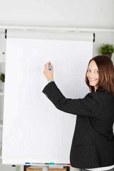 Smiling businesswoman with a blank flipchart — Stock Photo, Image