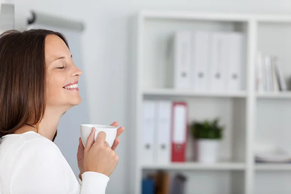 Mujer de negocios con los ojos cerrados sosteniendo la taza de café — Foto de Stock