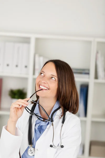 Läkaren tittar upp medan du håller glasögon i office — Stockfoto