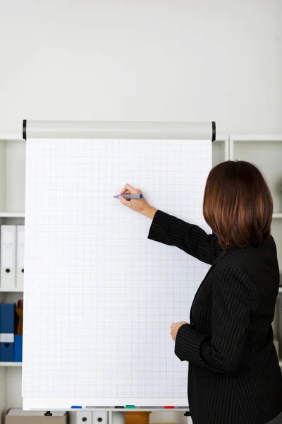 Affärskvinna skriva på blädderblock på kontor — Stockfoto