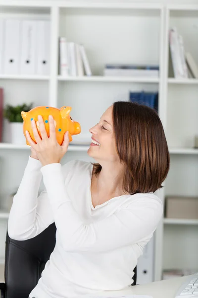 Geschäftsfrau hält Sparschwein, während sie es anschaut — Stockfoto