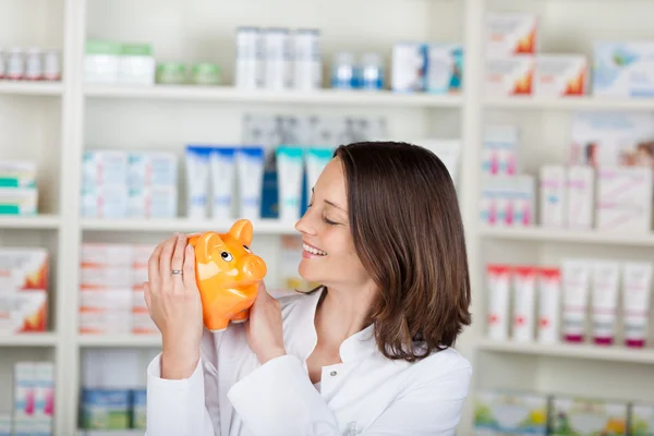 Farmacista guardando salvadanaio in farmacia — Foto Stock