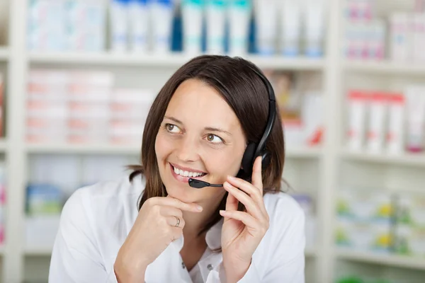 Geschäftsfrau unterhält sich auf Kopfhörer in Apotheke — Stockfoto