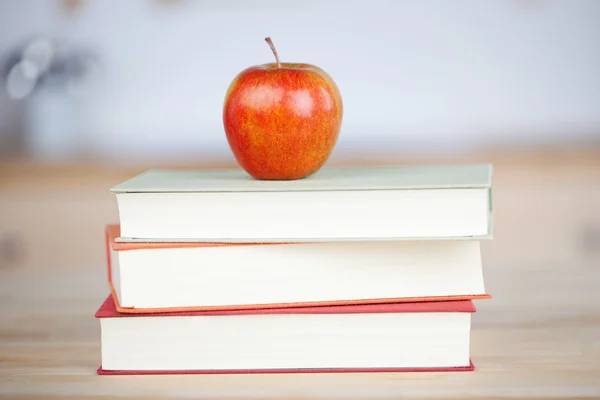 Czerwone jabłko na książki ułożone na stole — Zdjęcie stockowe