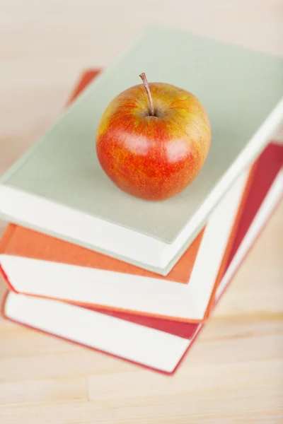 Manzana en libros apilados en la mesa — Foto de Stock